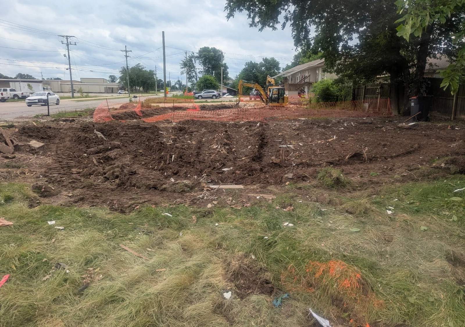Cleared ground and active excavation beside an Arkansas street